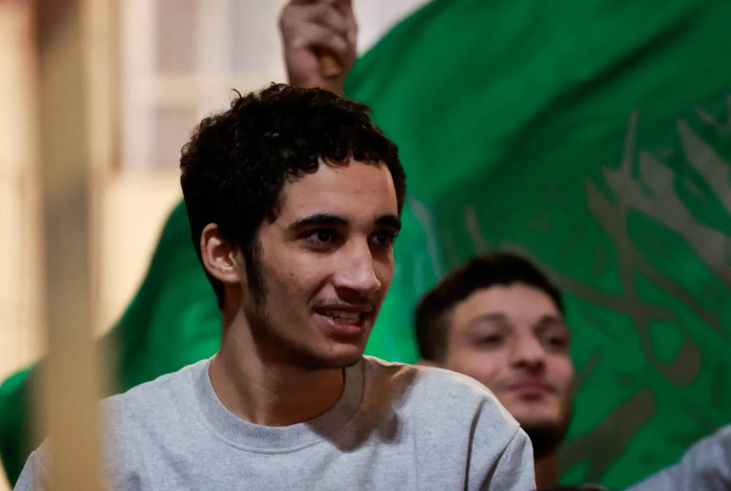 أحد الأسرى الفلسطينيين المفرج عنهم من السجون الإسرائيلية يحمل علماً أخضر بعد إطلاق سراحه (رويترز)