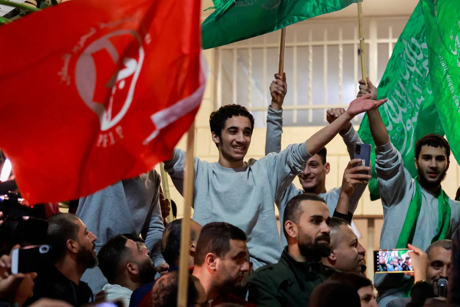 أحد الأسرى الفلسطينيين المفرج عنهم من السجون الإسرائيلية يحمل علماً أخضر بعد إطلاق سراحه (رويترز)