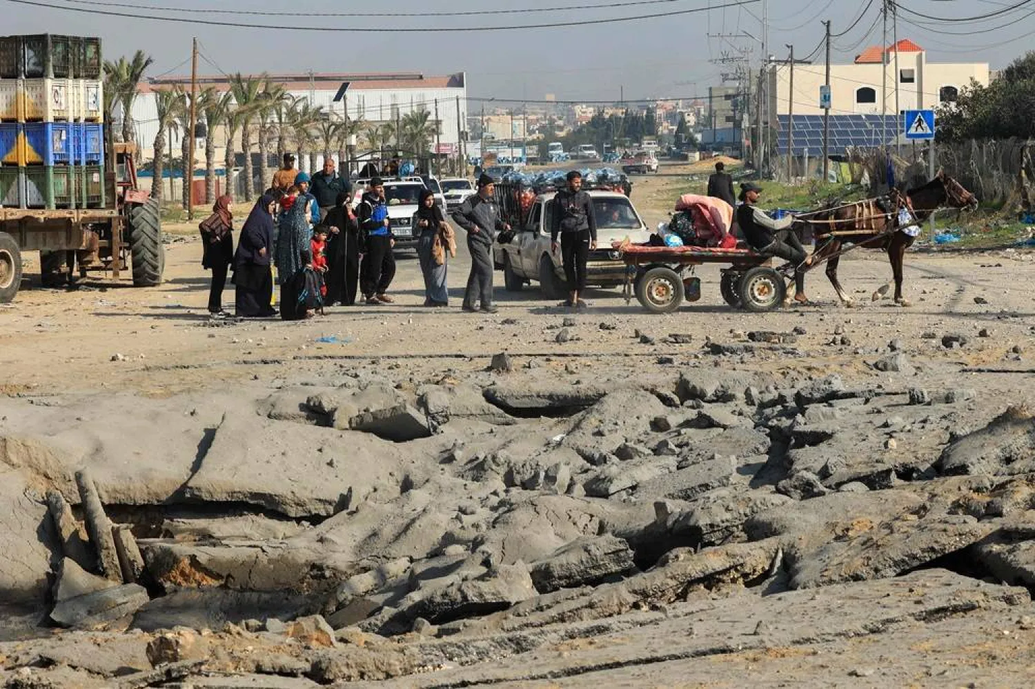 Palestinians stand next to a crater following an Israeli airstrike on the main road between Rafah and Khan Yunis on the southern Gaza Strip, on December 2, 2023, amid continuing battles between Israel and the militant group Hamas. (AFP)
