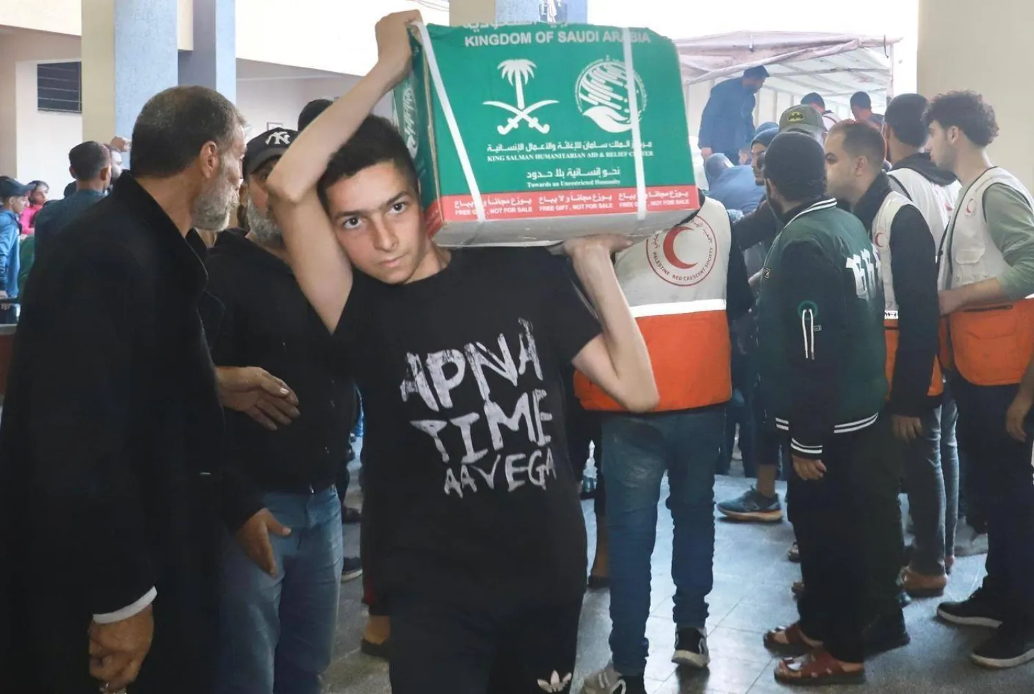 شاب فلسطيني يحمل صندوق مساعدات إغاثية سعودية خلال توزيعها في غزة (واس)