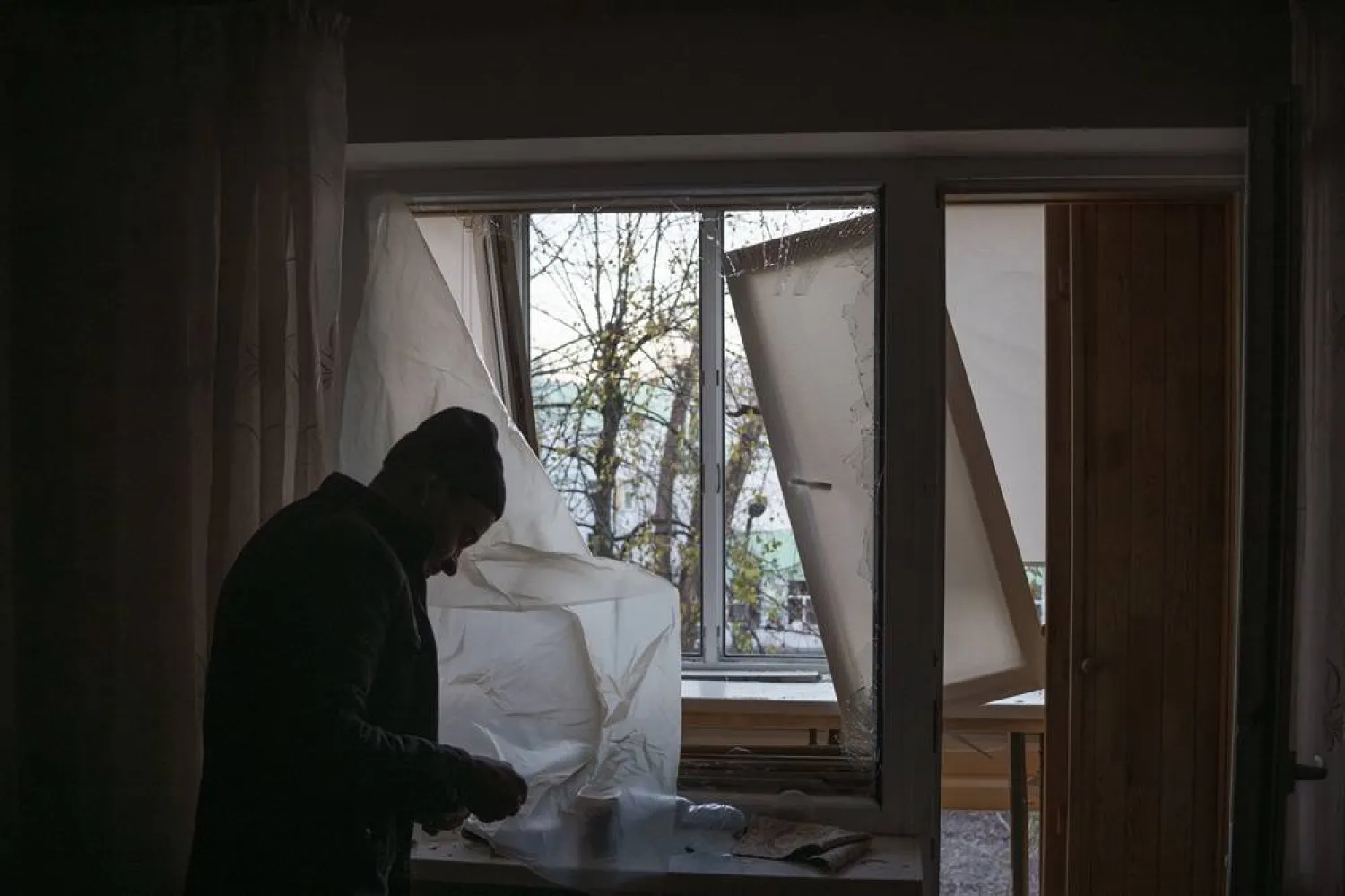 A man uses plastic to cover a broken window in his apartment following a Russian drone attack in Kyiv, Ukraine, Saturday, Nov. 25, 2023. (AP)