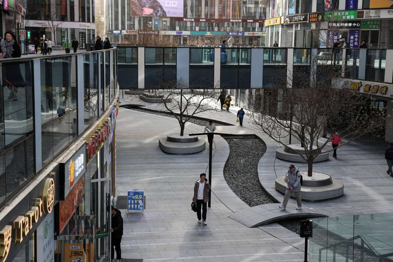 People walk at a shopping compound in Beijing, China December 6, 2023. REUTERS/Tingshu Wang