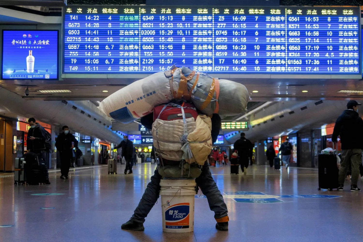 FILE PHOTO: A traveller is seen with his belongings at a railway station, following the coronavirus disease (COVID-19) outbreak, in Beijing, China January 13, 2021. REUTERS/Thomas Peter/File Photo