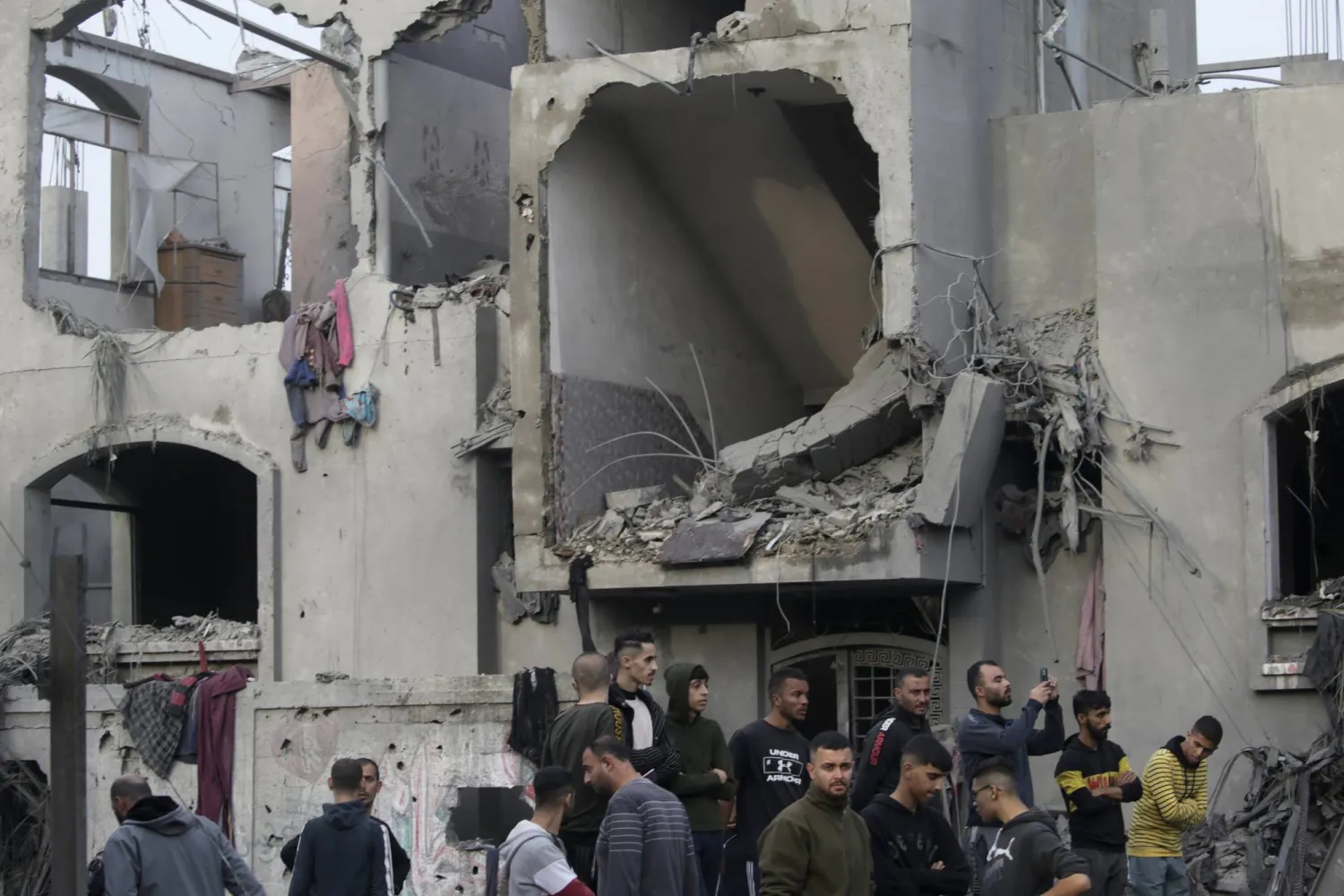 فلسطينيون يتفقدون منزلًا مدمرا لعائلة بركة في أعقاب الغارات الجوية الإسرائيلية في دير البلح (إ.ب.أ)