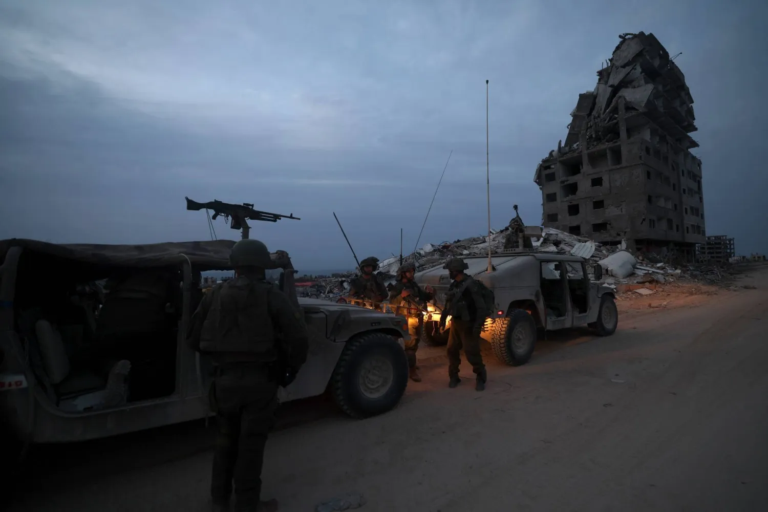 جنود إسرائيليون يظهرون إلى جانب آليات عسكرية في بيت لاهيا بضواحي مدينة غزة (إ.ب.أ)