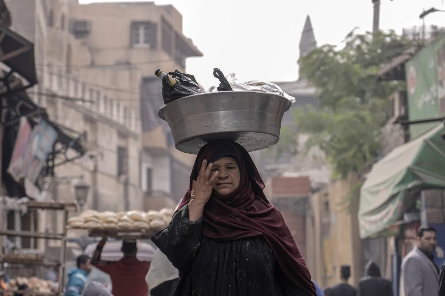 A woman balances her bowl as she walks in the Old Cairo district of Cairo, Egypt, Friday, Dec. 8, 2023. (AP Photo/Amr Nabil)