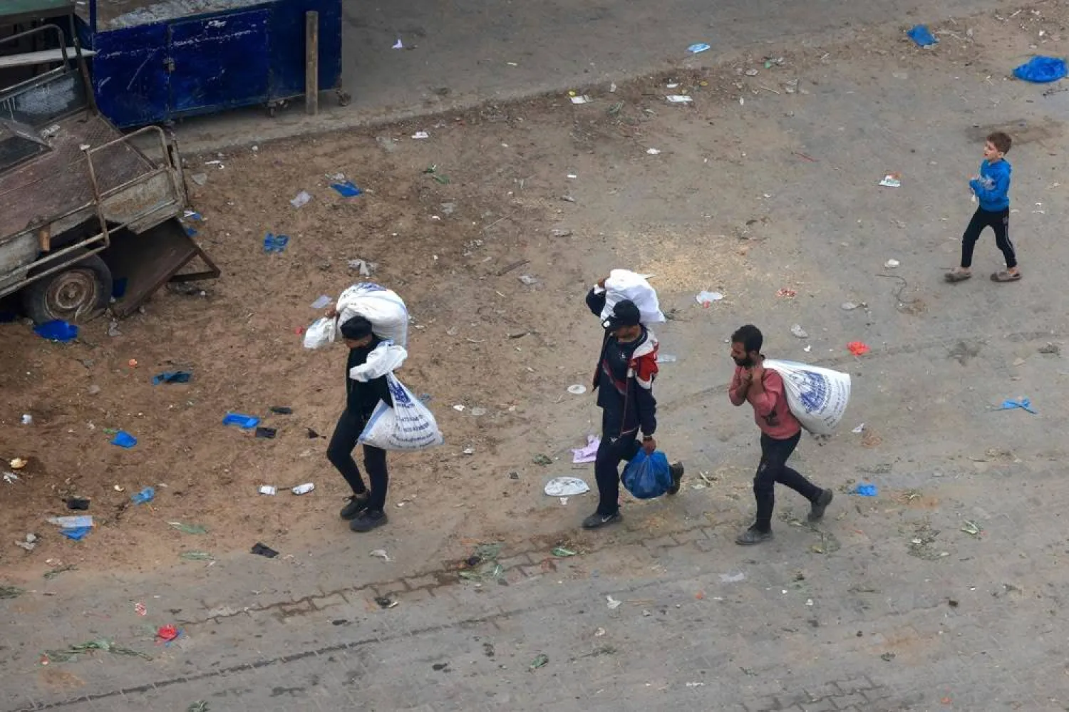 Palestinians carry bags of foodstuff in Rafah in the southern Gaza Strip, on December 10, 2023, amid ongoing battles between Israel and the Palestinian movement Hamas. (AFP)