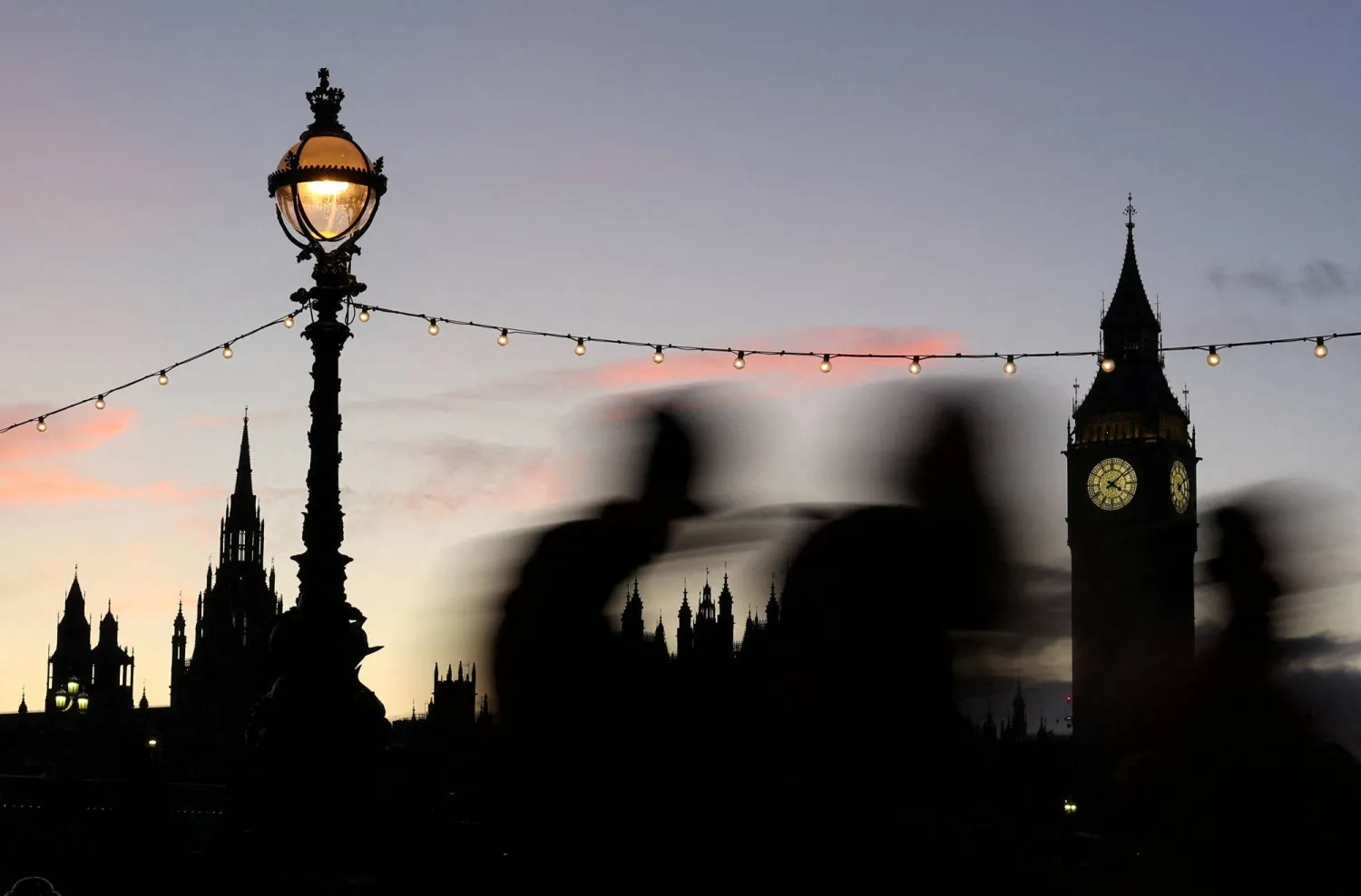 People walk past the Elizabeth Tower, more commonly known as Big Ben, and the Houses of Parliament at dusk in London, Britain, December 12, 2023. REUTERS/Toby Melville    