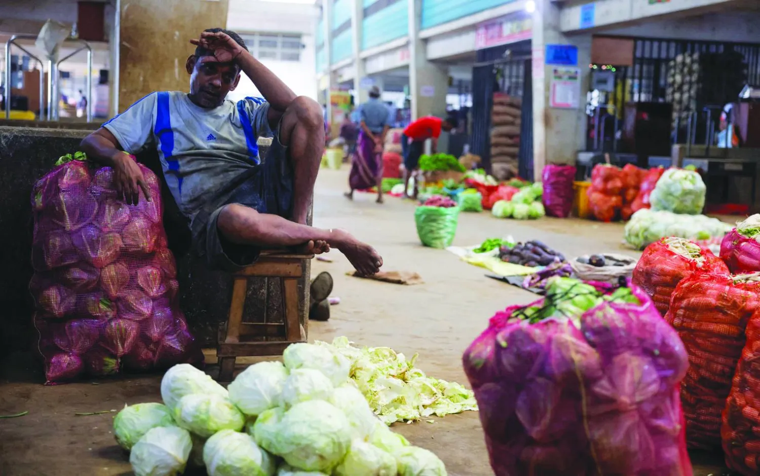 بائع ينتظر الزبائن في كشك لبيع الخضار في سوق رئيسية في سريلانكا (رويترز)