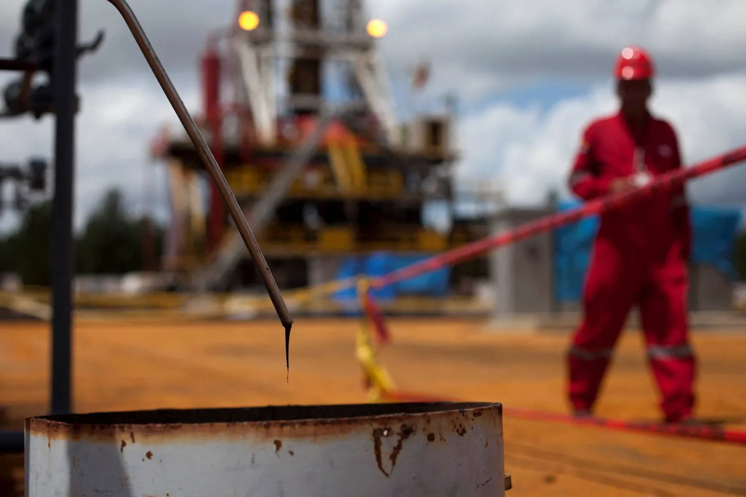 FILE PHOTO: Crude oil drips from a valve as a worker walks past at an oil well operated by Venezuela's state oil company PDVSA in Morichal July 28, 2011. REUTERS/Carlos Garcia Rawlins/File Photo