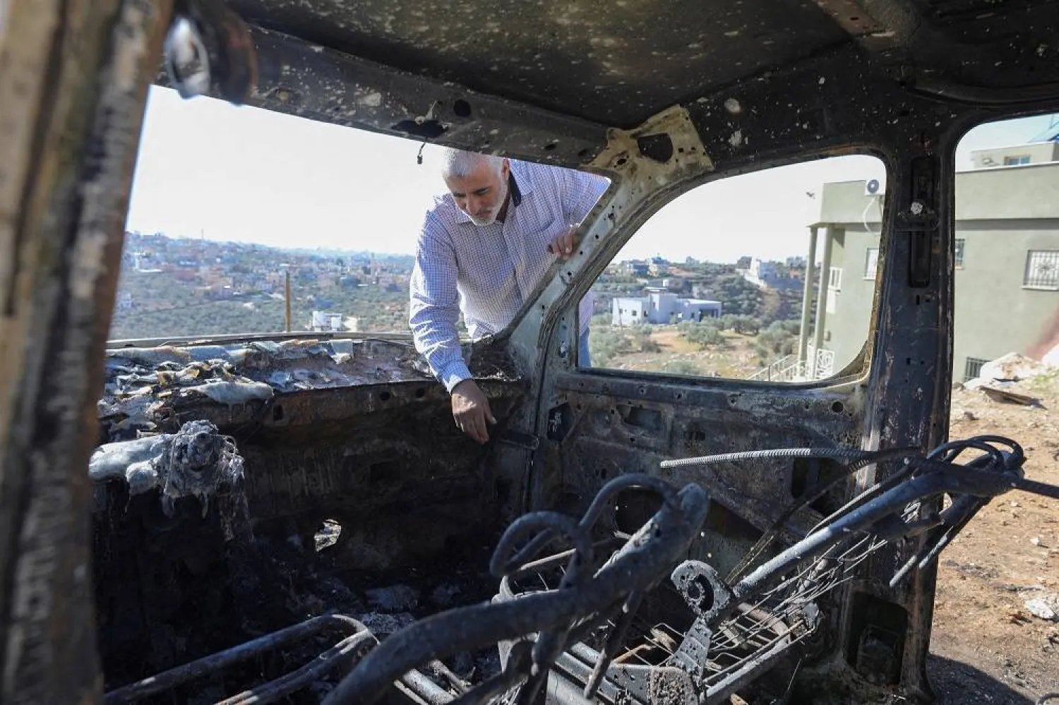 A Palestinian checks a car burned in Israeli settlers raid near Salfit in the Israeli-occupied West Bank December 3, 2023. (Reuters)