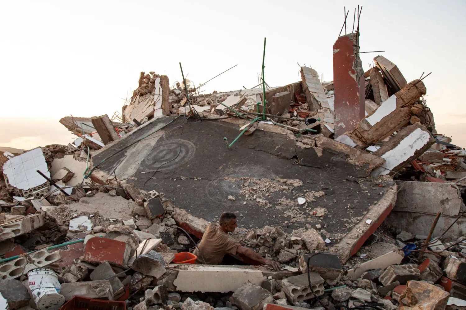 A man checks the ruins of a house after an Israeli air raid in Majdal Zoun on December 17, 2023, amid increasing cross-border tensions as fighting continues with Hamas in the southern Gaza Strip. (Photo by Hassan FNEICH / AFP)