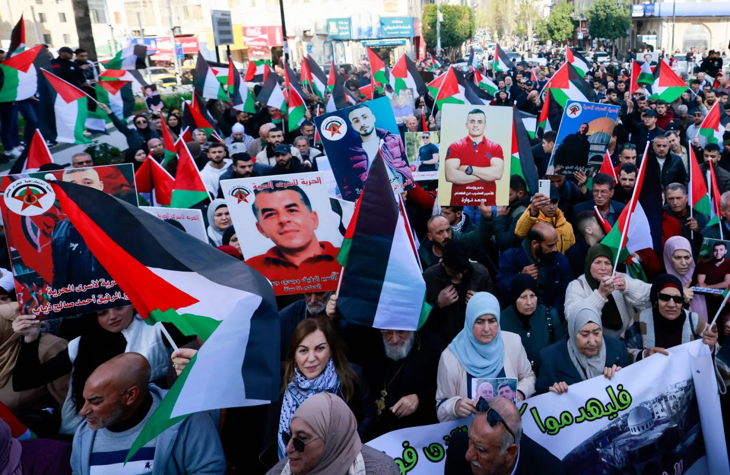 أعلام فلسطينية وصور لسجناء فلسطينيين خلال مظاهرة في رام الله يوم 14 ديسمبر 2023 (أ.ف.ب)