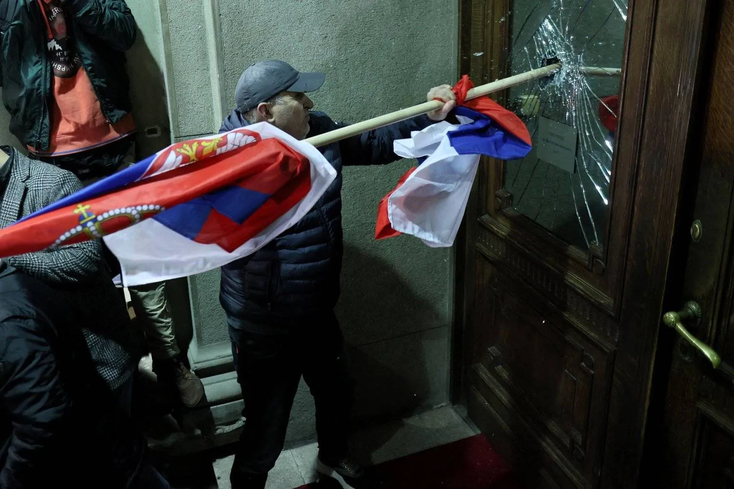 A demonstrator smashes the glass of a door during a protest in front of the Belgrade municipality building on Sunday. (AFP) 

