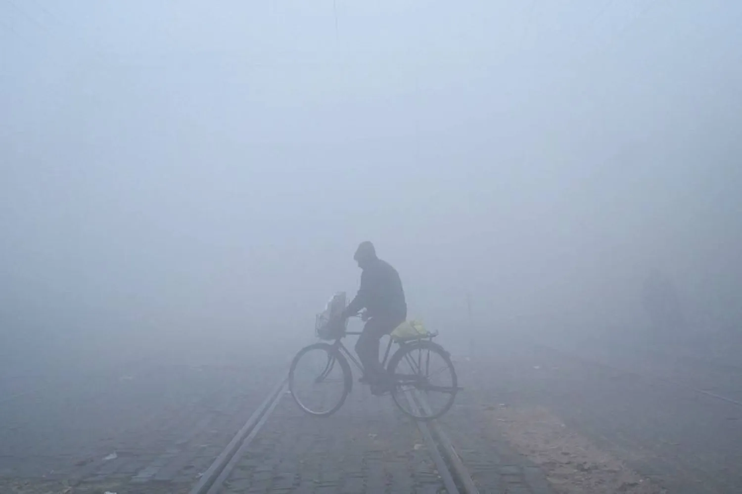 A cyclist crosses a railway track amid dense fog on a cold winter morning in Amritsar on December 26, 2023. (AFP)