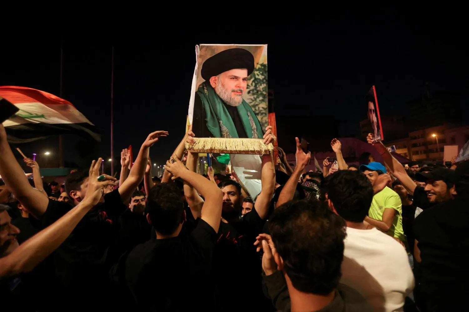 أنصار مقتدى الصدر يرفعون صورته في مظاهرة ببغداد (رويترز)