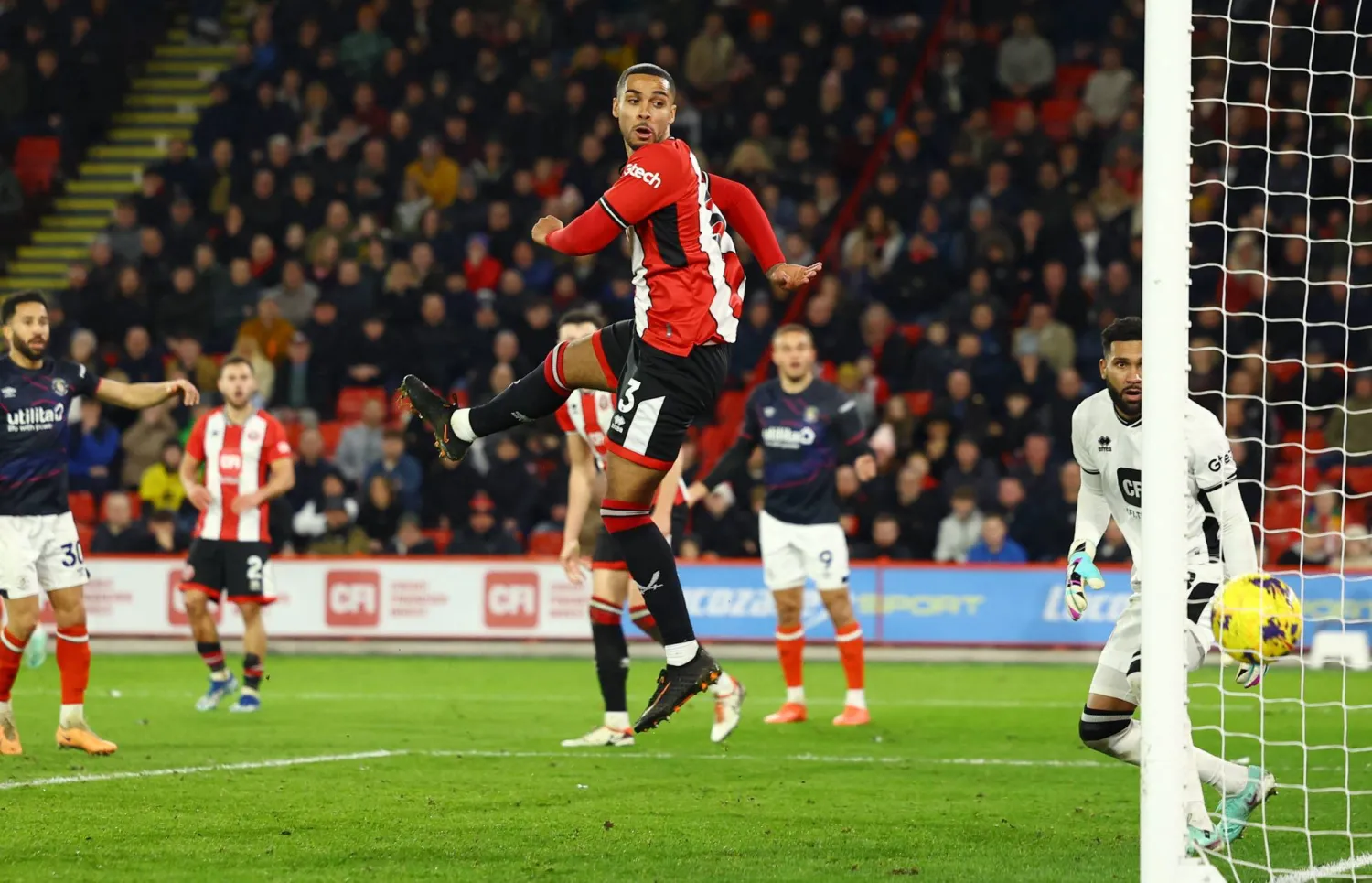 أنيس بن سليمان لاعب شيفيلد يونايتد أثناء تسجيله هدفاً في مرمى فريقه بالخطأ خلال مواجهة لوتون تاون في الدوري الإنجليزي (رويترز)