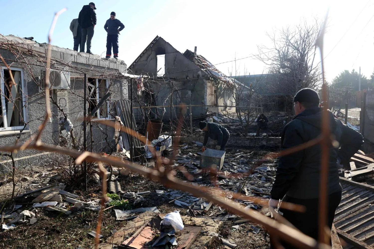 سكان محليون يقومون بتنظيف الحطام في فناء منزل دُمّر نتيجة هجوم بطائرة دون طيار في تايروف بمنطقة أوديسا (أ.ف.ب)