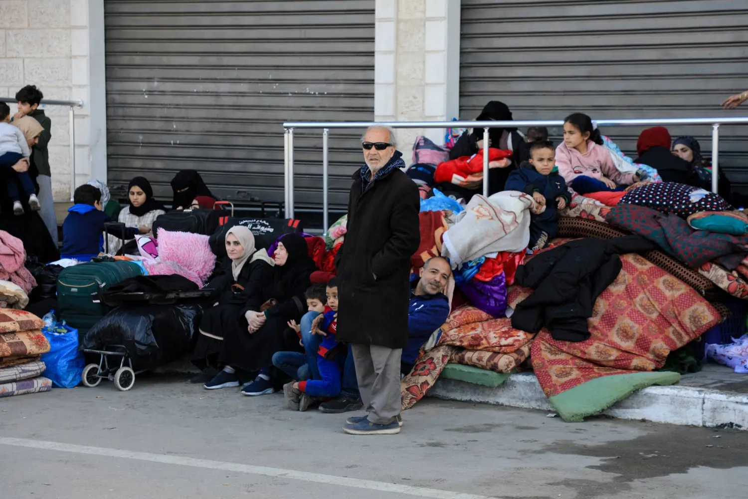 فلسطينيون يستريحون بجوار ممتلكاتهم خلال فرارهم من منازلهم بعد أن أمرهم الجيش الإسرائيلي بإخلاء المنطقة في البريج وسط قطاع غزة (رويترز)