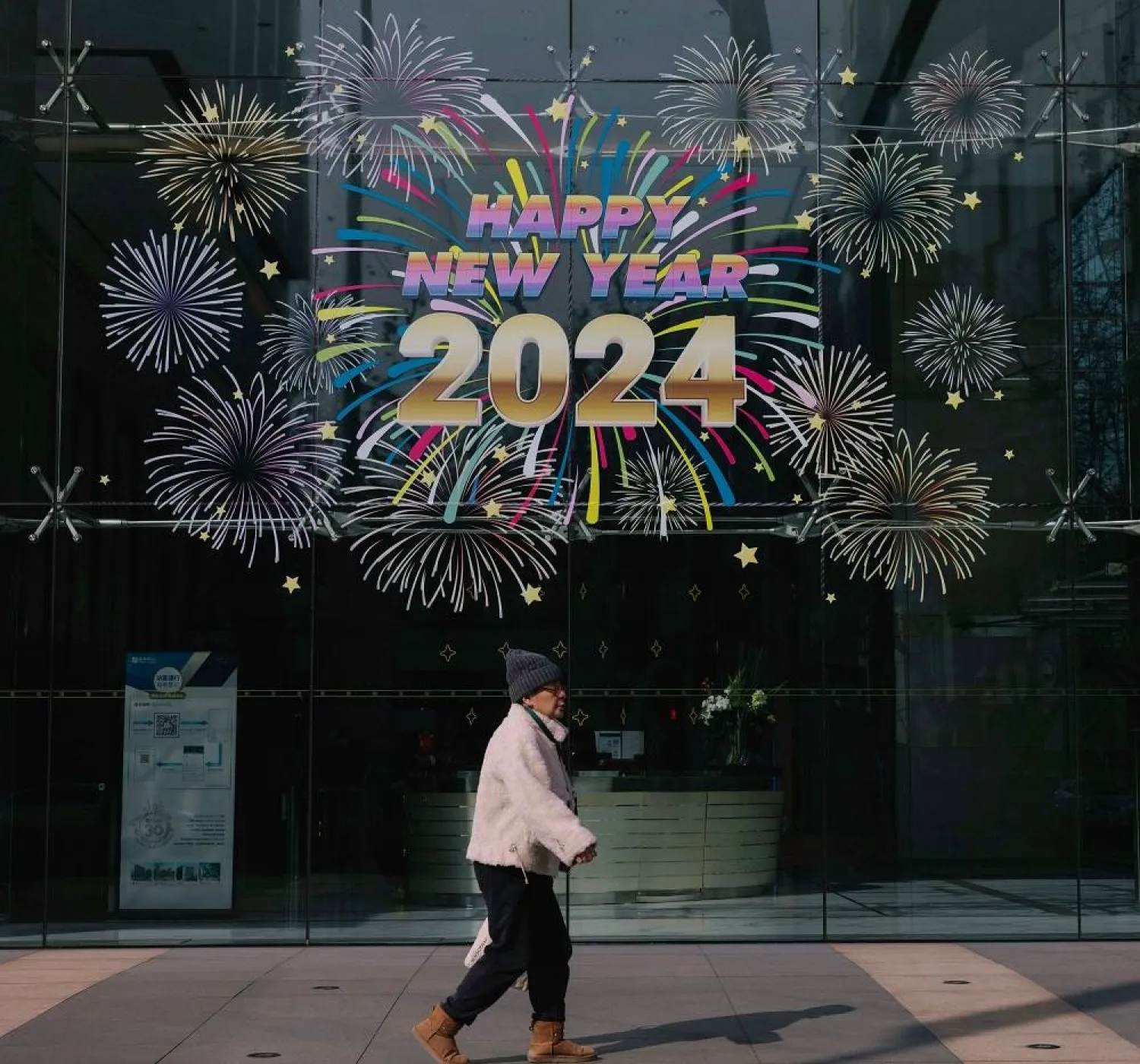 A person walks on the street past decorations for the celebration of 2024 New Year, in Shanghai, China, 29 December 2023. (EPA)