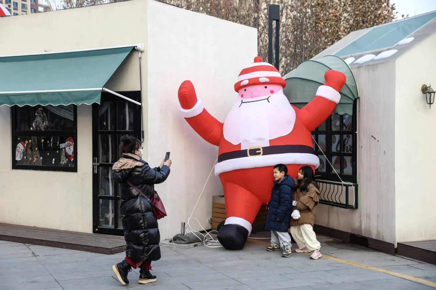 A woman takes a photograph of her children with a Christmas-themed decoration ahead of the celebration of 2024 New Year, in Beijing, China, 30 December 2023. EPA/WU HAO