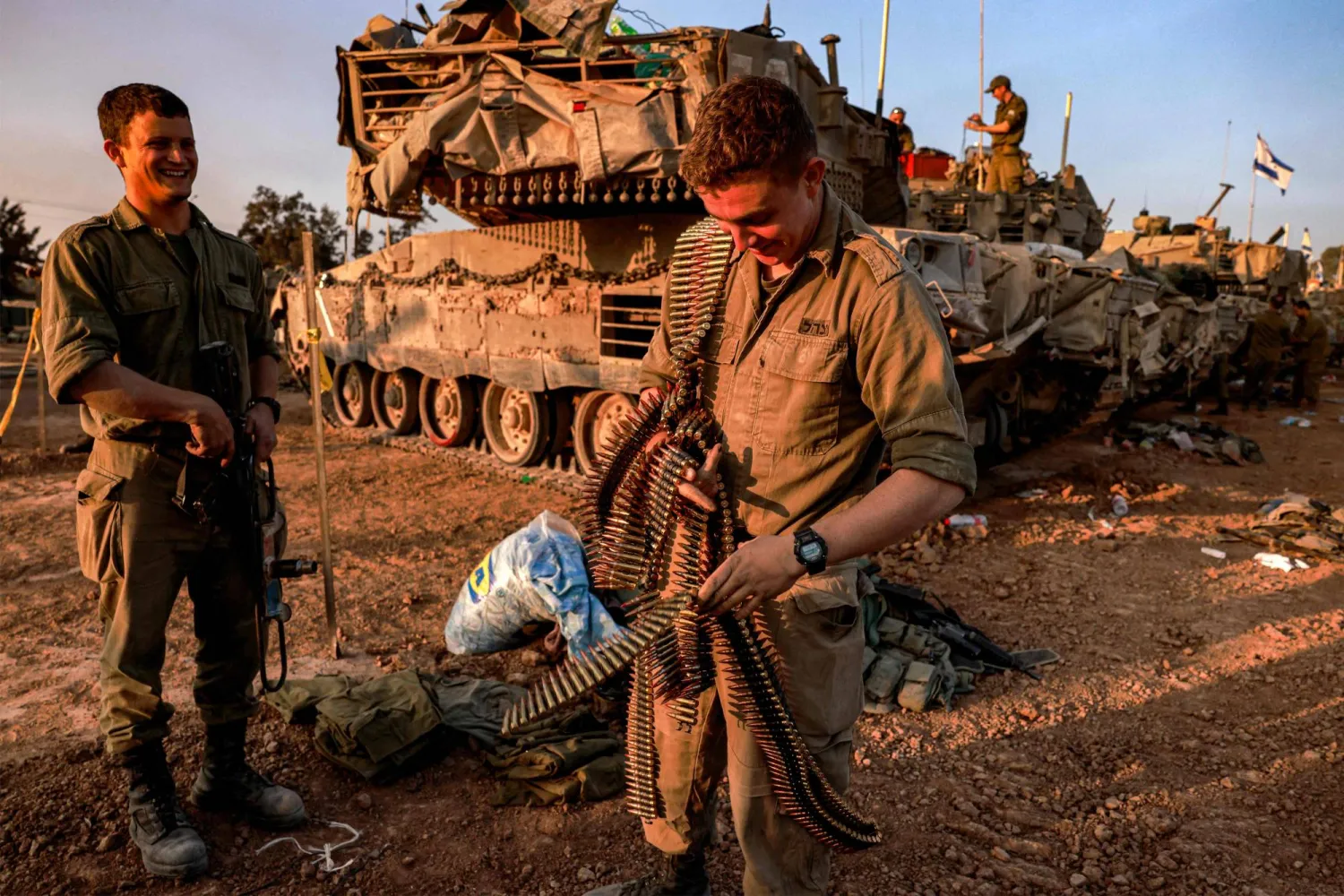 جندي إسرائيلي يحمل أحزمة رصاص بجوار دبابة على حدود قطاع غزة (أ.ف.ب)