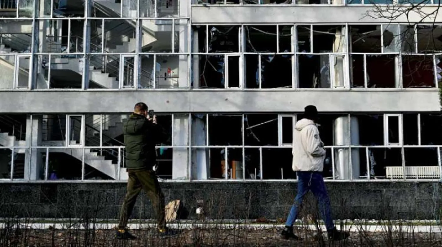 أوكرانيون يعاينون مؤسسة تعليمية في كييف تضررت بفعل قصف أمس (أ.ف.ب)