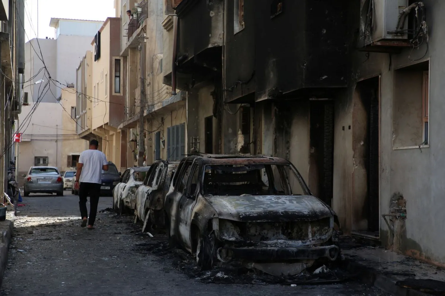 A man walks next to burned cars after clashes in Tripoli, Libya August 28, 2022. REUTERS/Hazem Ahmed
