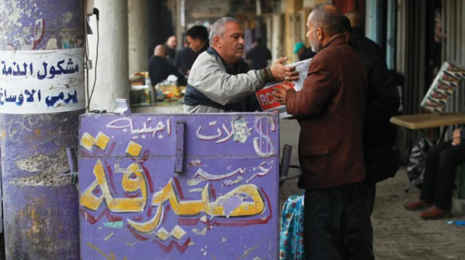A street money exchanger counts banknotes at al-Kifah stock market in Baghdad on December 27, 2022 as the value of Iraqi dinar against US dollar drops further. (AFP)