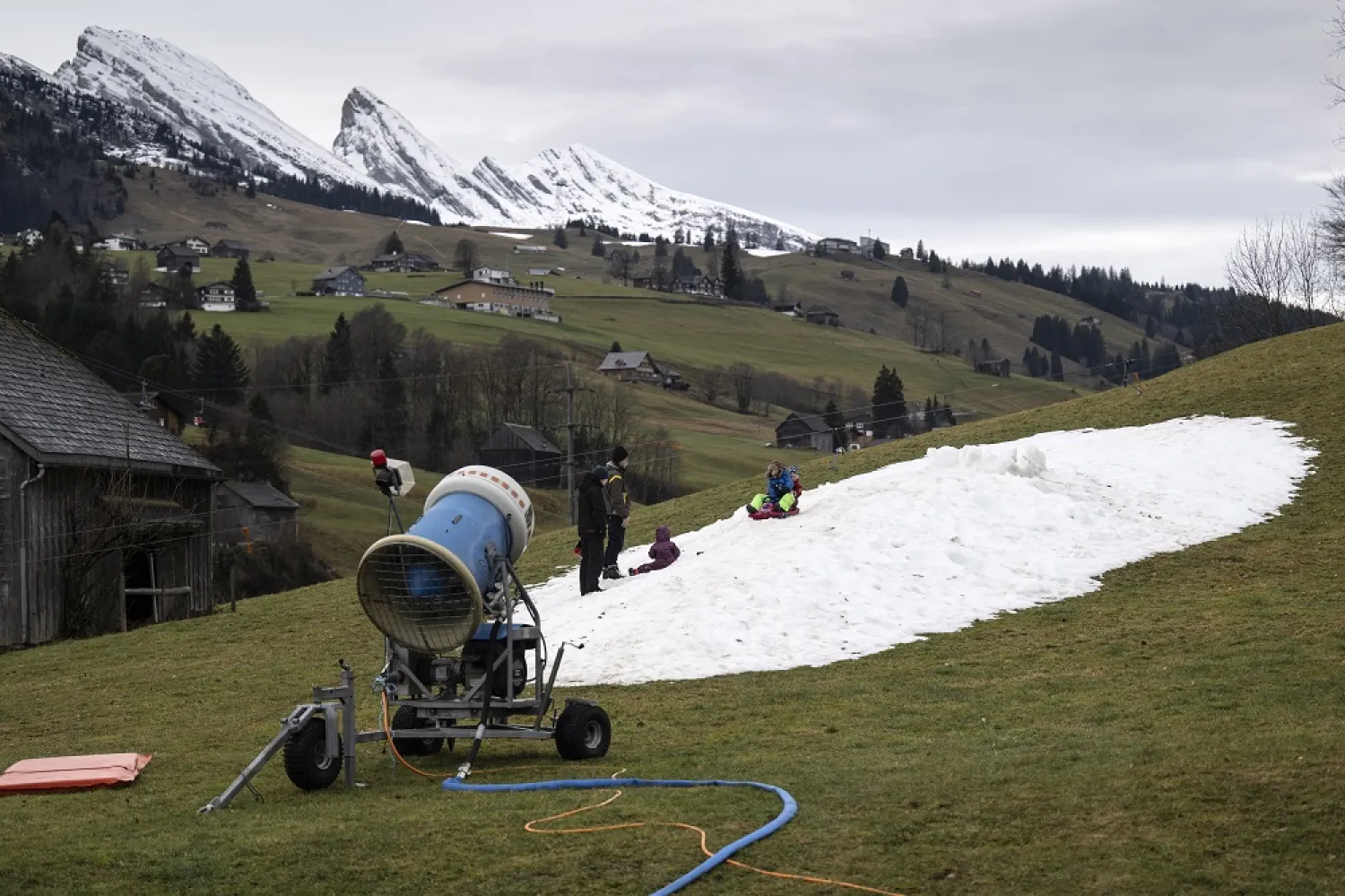 Children play on a patch of artificial snow, in Wildhaus, Switzerland, 04 January 2023. (EPA)