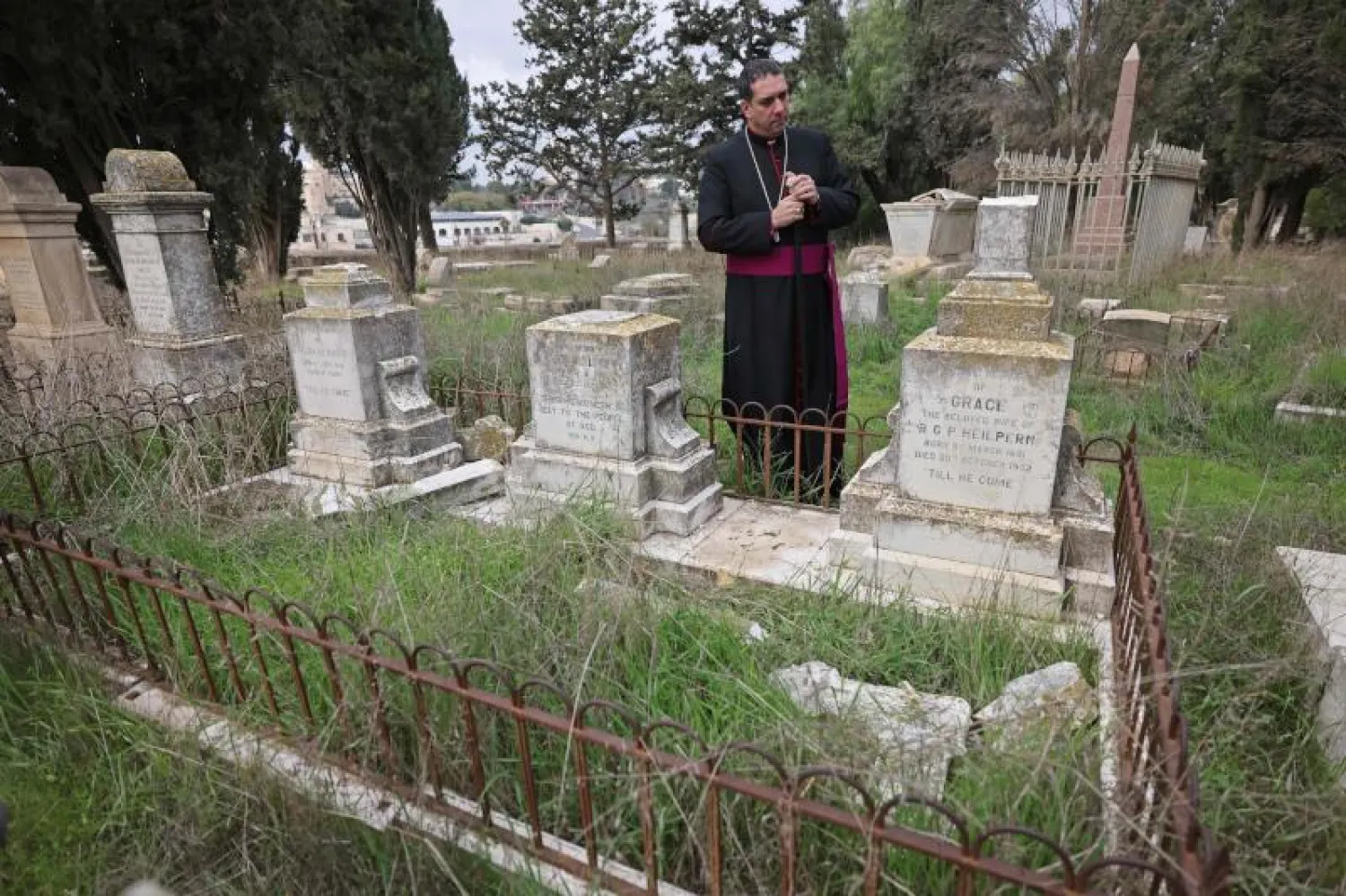 رجل الدين المسؤول عن المقبرة يعاين الاعتداء (أ.ف.ب)