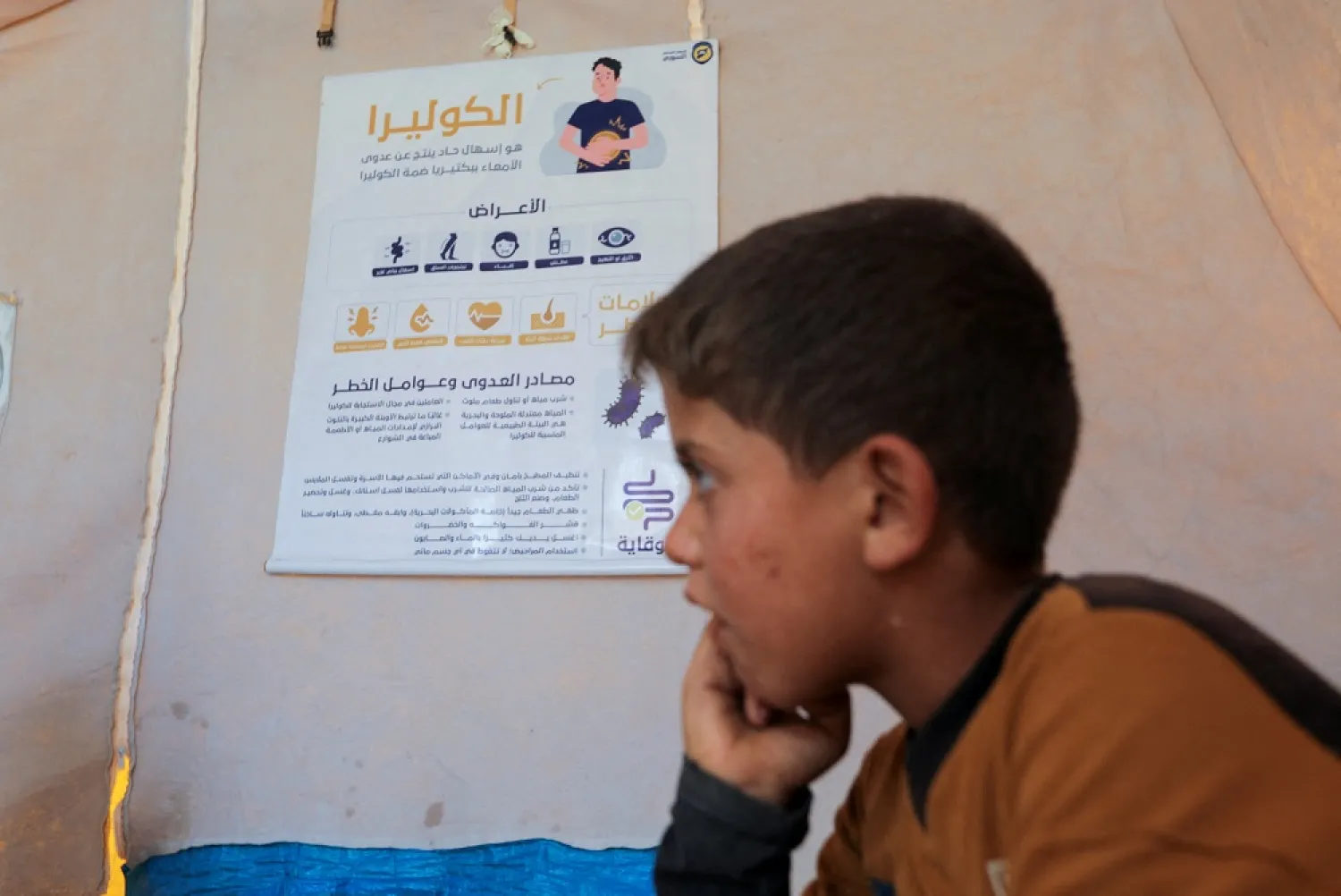 An internally displaced boy listens to civil defense members during a cholera awareness campaign, at a camp in northern opposition-held Idlib, Syria September 24, 2022. (Reuters)