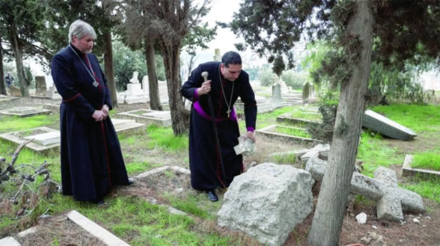 Hıristiyan iki din adamı, 4 Ocak'ta Kudüs'teki Protestan mezarlığına uygulanan vandalizmi inceledi. (Reuters)