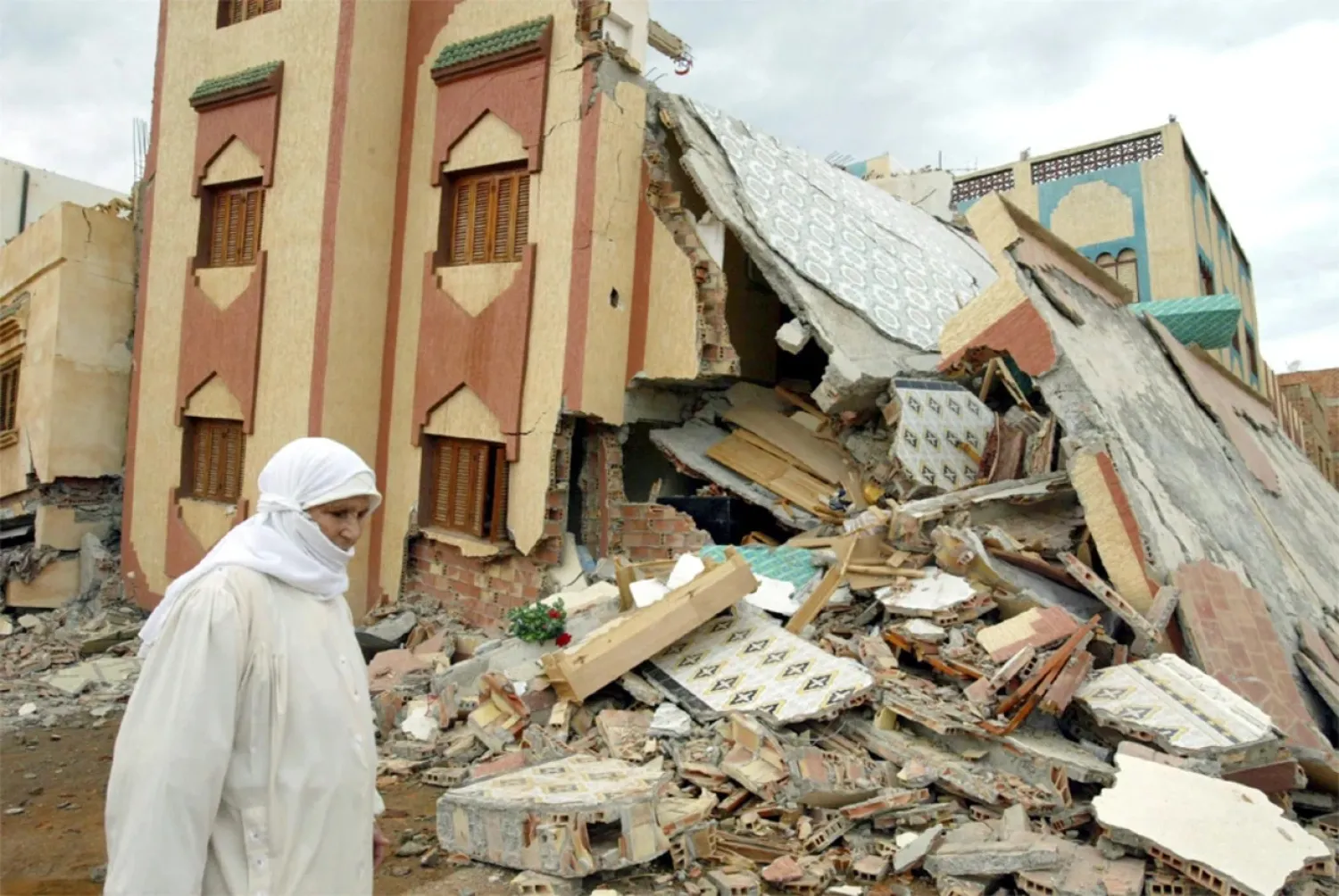 AFP file photo: A woman passes by a collapsed building in the Moroccan town of Imzouren after an earthquake.