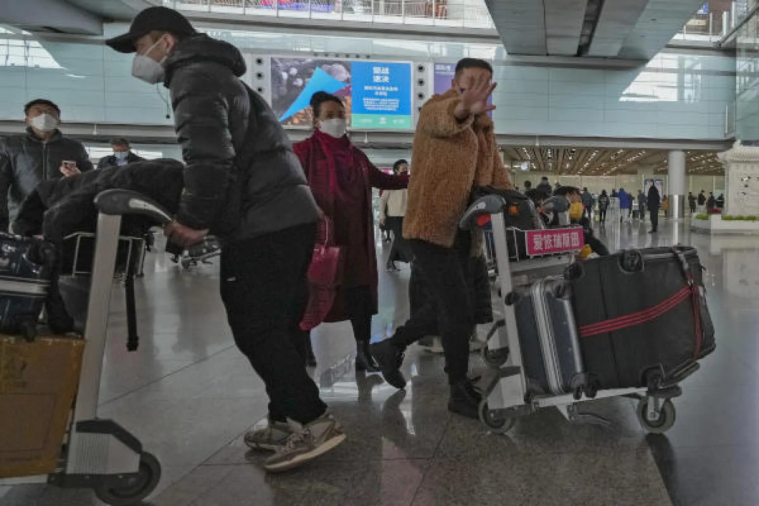 A man from Hong Kong reacts to having his photo taken as he arrives at Terminal 3 international arrival hall of the Beijing Capital International Airport in Beijing, Sunday, Jan. 8, 2023. (AP Photo/Andy Wong)
