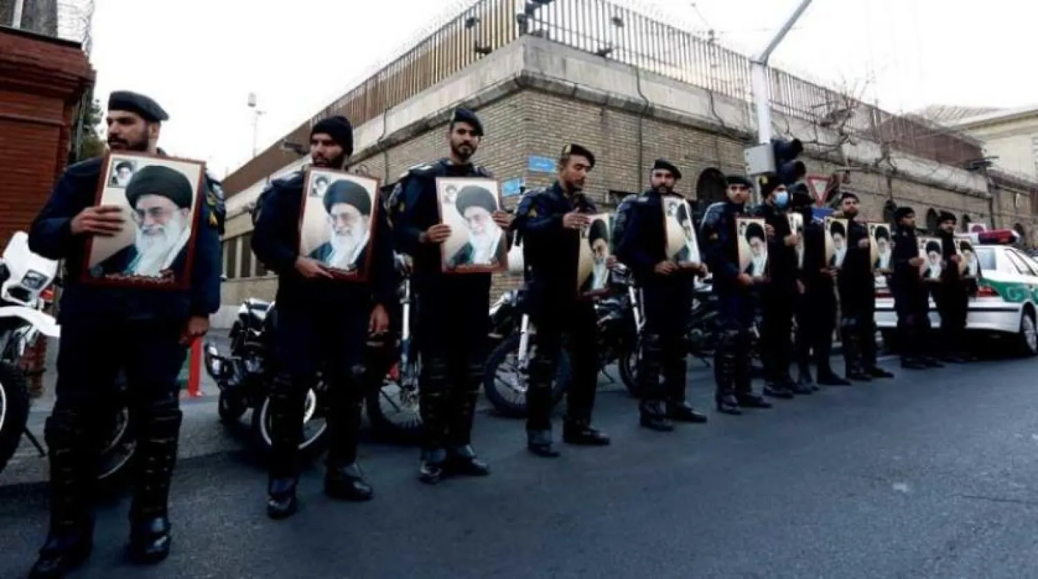 Iranian riot police hold pictures of Khamenei during a protest in front of the French embassy in Tehran (EPA) 

