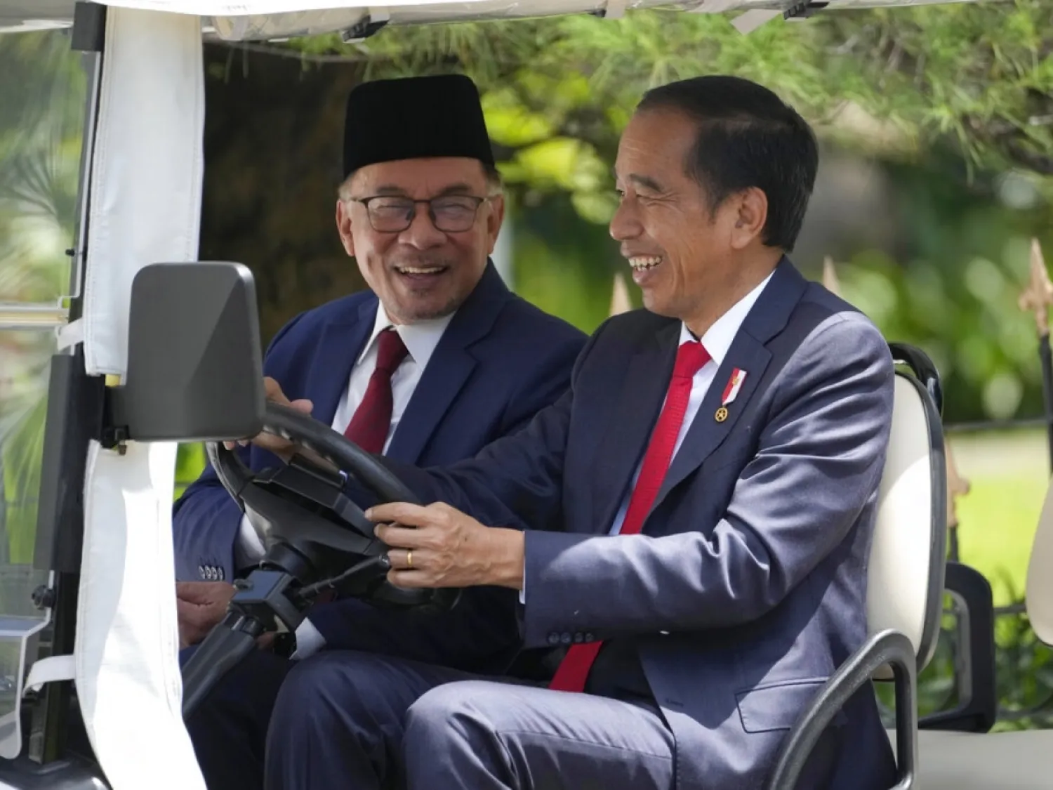 Joko Widodo, right, drives Anwar Ibrahim around the presidential palace's gardens in an electric buggy ahead of talks. Photo: AP
