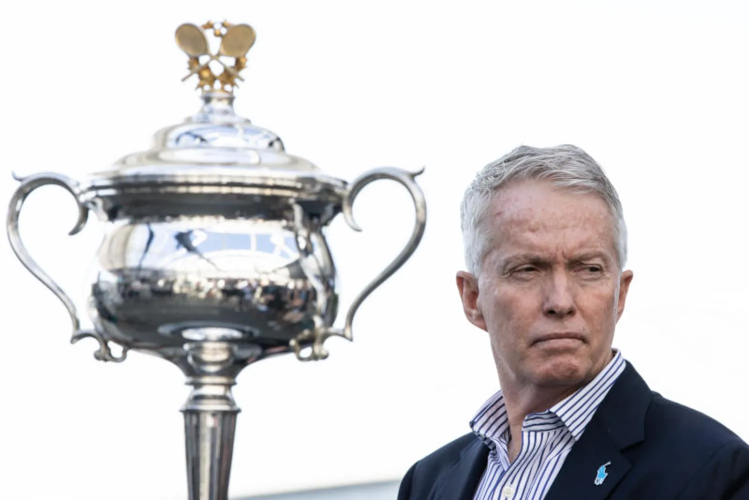 مدير بطولة أستراليا المفتوحة للتنس كريج تيلي يتحدث لوسائل الإعلام وبجانبه كأس البطولة (د.ب.أ)