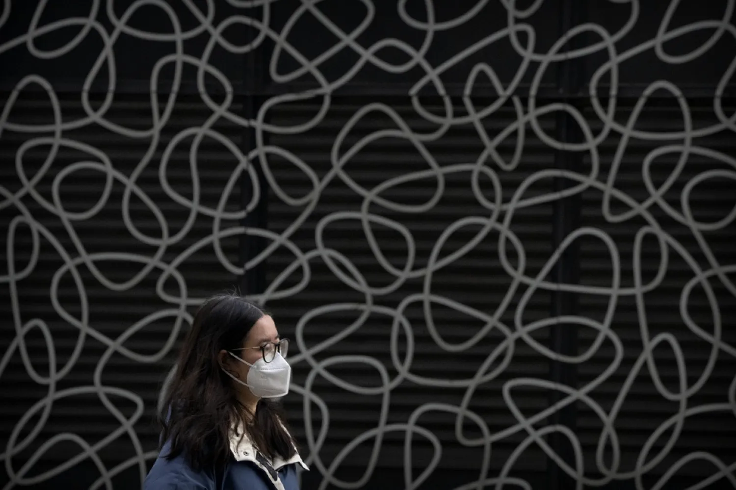A woman wearing a face mask walks at a shopping and office complex in Beijing, Wednesday, Jan. 11, 2023. (AP)