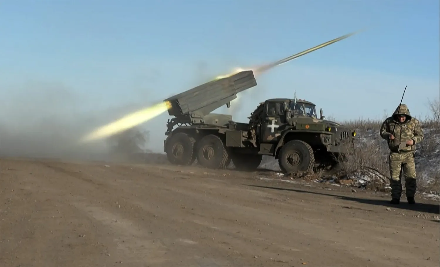 This grab taken from AFP video footage shows a member of Ukraine's military looking away as a BM-21 Grad MLRS 122mm rocket launcher fires on the outskirts of Soledar on January 11, 2023. (AFP)