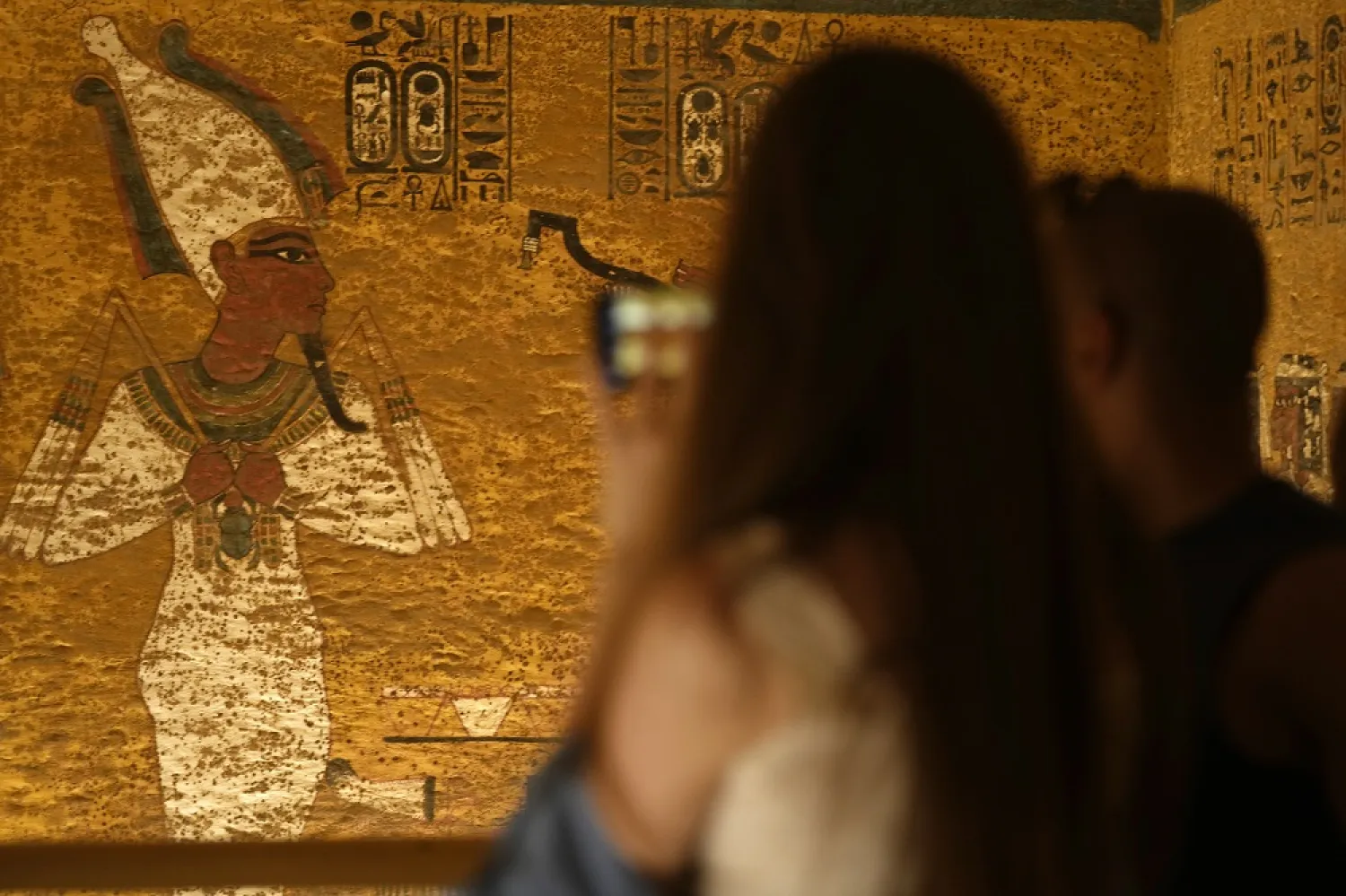 Tourists look at murals inside King Tutankhamun's burial chamber as Egypt marks the 100th anniversary of its discovery, in the Valley of the Kings in Luxor, Egypt, 04 November 2022. (EPA)