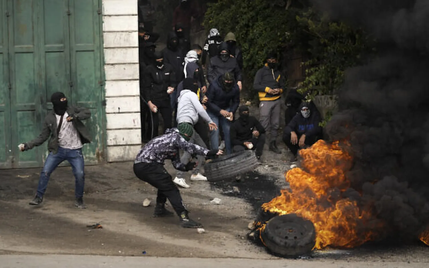 File photo: Masked Palestinians burn tires during clashes with Israeli security forces following the funeral of Mufid Khalil in the West Bank village of Beit Ummar, near Hebron, November 29, 2022. (AP Photo/Mahmoud Illean)
