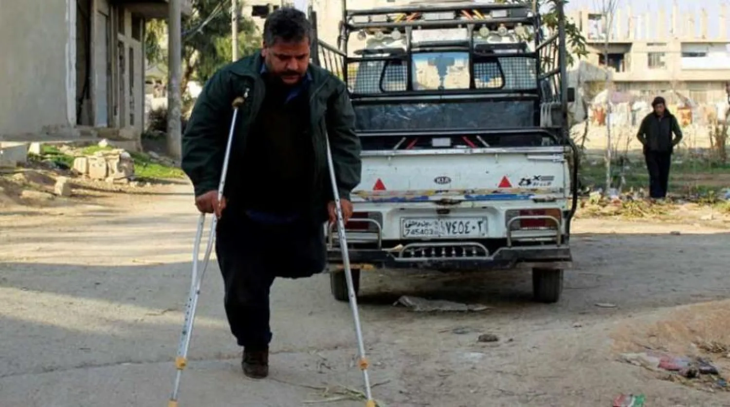 Ebu Muhammed, 2018'de bir mayın patlamasında bacağını kaybetti. Doğu Guta, Kafr Batna'da koltuk değnekleriyle yürüyor (Reuters)