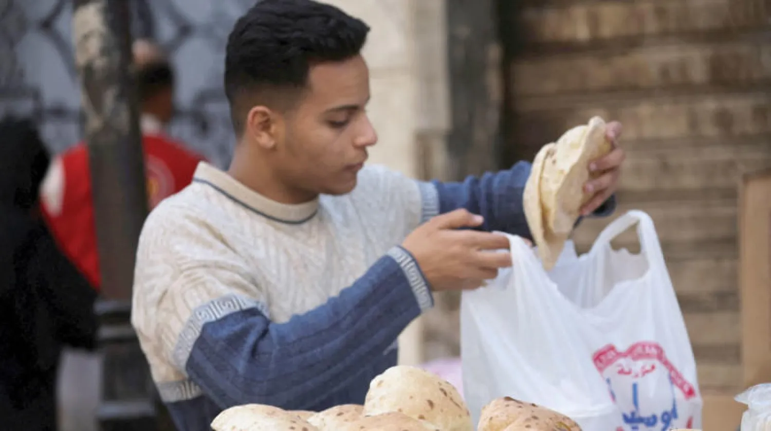 رجل في إحدى أسواق القاهرة يوم الثلاثاء يشتري أرغفة الخبر (رويترز)