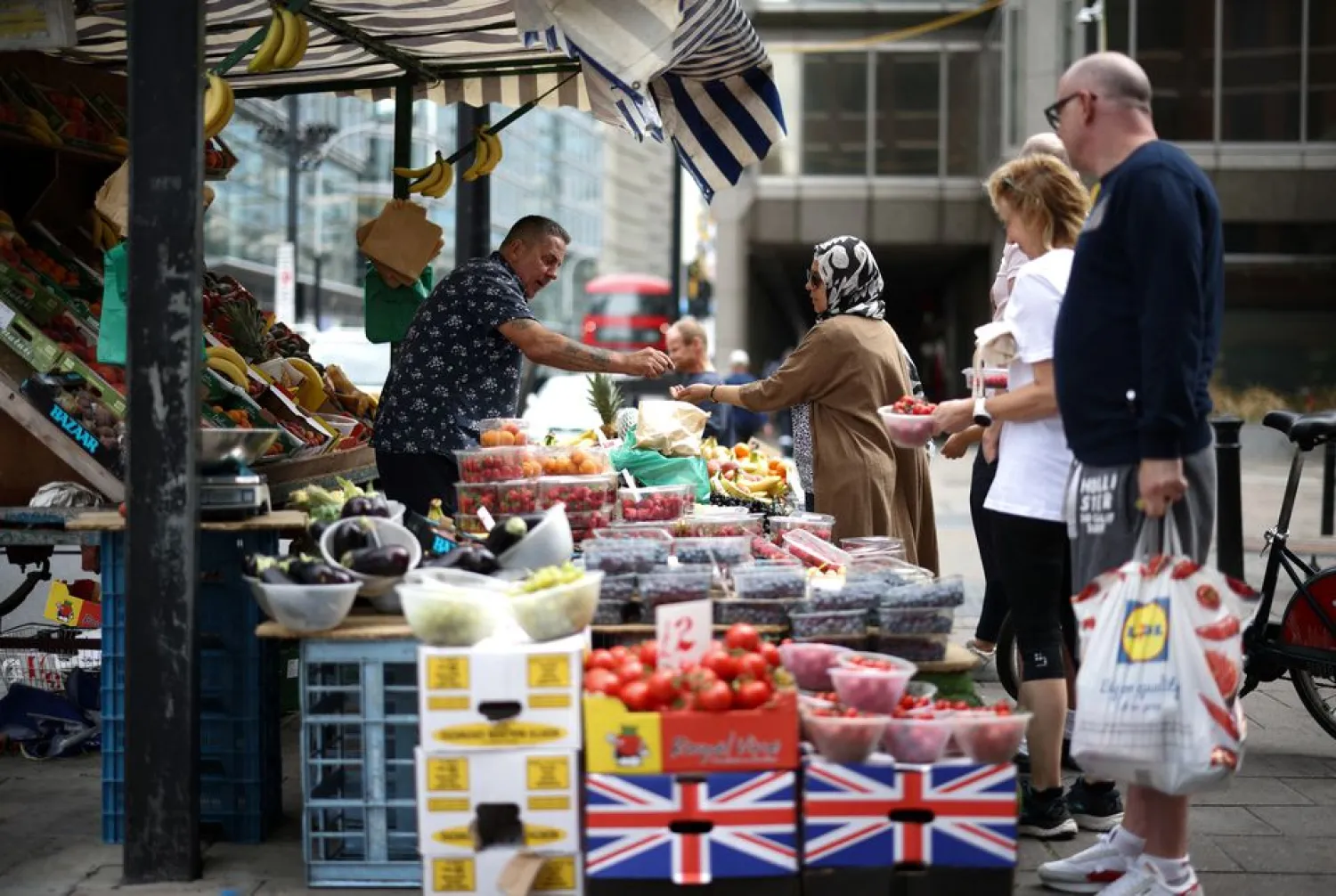 A person buys produce from a fruit and vegetable market stall in central London, Britain, August 19, 2022. REUTERS/Henry Nicholls/File Photo







