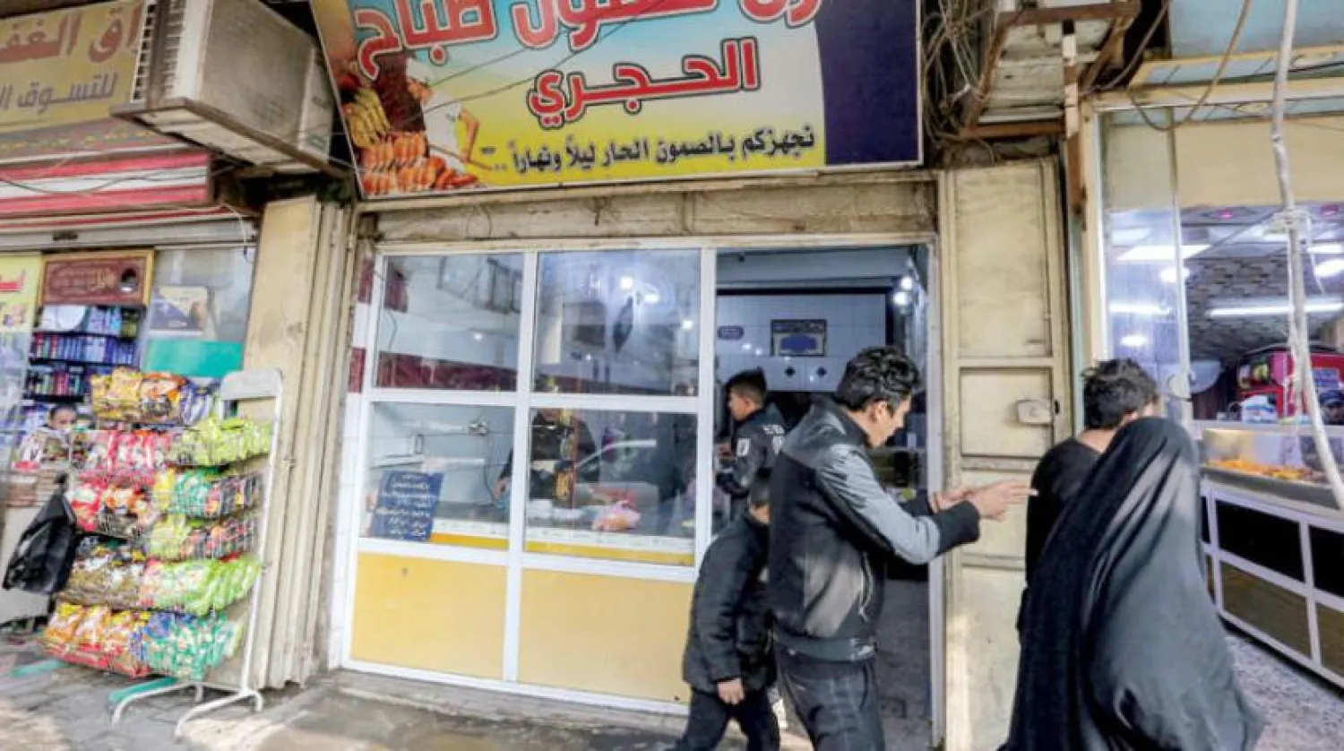 Dolar krizi nedeniyle fiyatların yükseldiği Irak’ta başkent Bağdat'taki bir fırından ekmek alan Iraklılar (AFP)