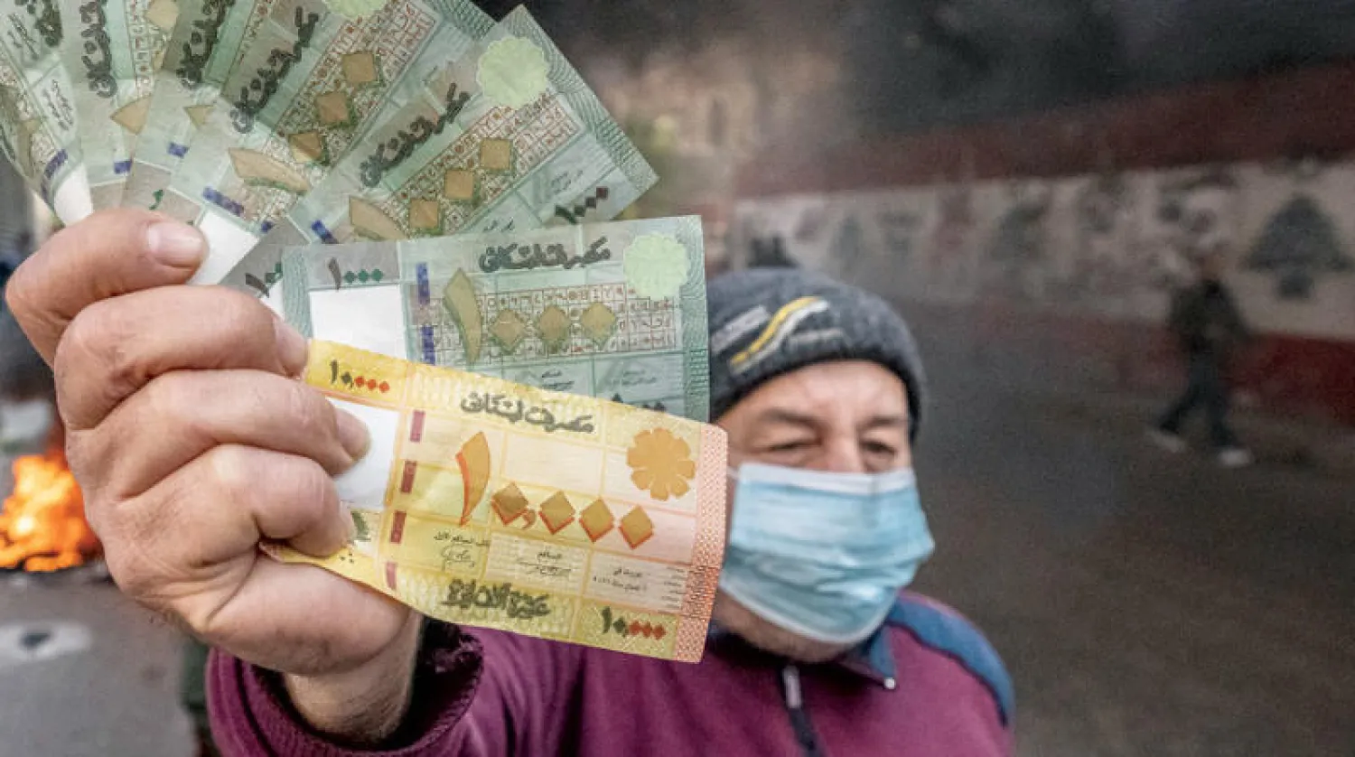 لبناني يحمل أوراقاً من العملة الوطنية التي تتراجع قيمتها بشكل يومي (أ.ب)