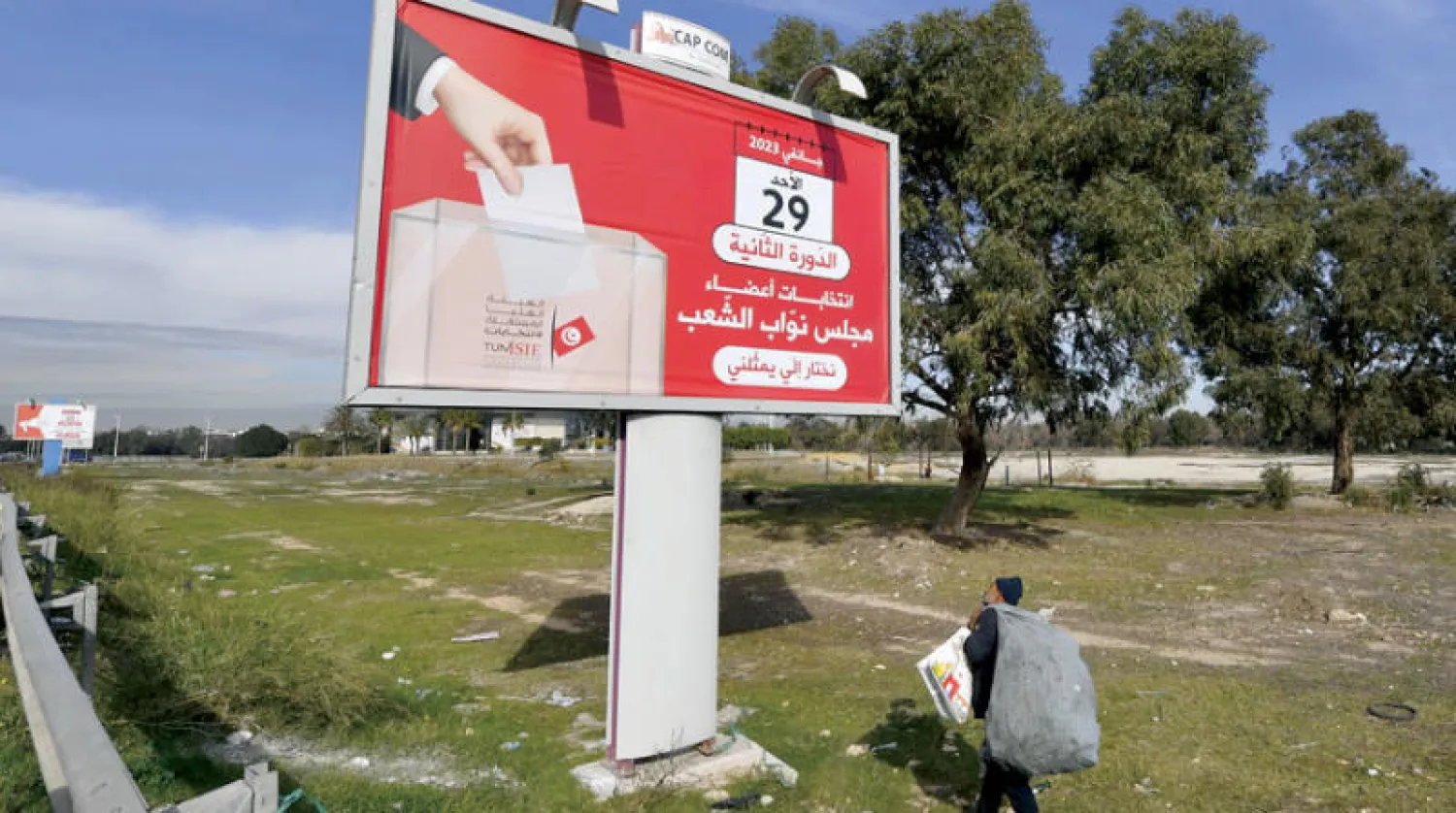 تونسي يمر بجانب إعلان يدعو الناخبين للتوجه إلى صناديق الاقتراع غداً الأحد (أ.ف.ب)