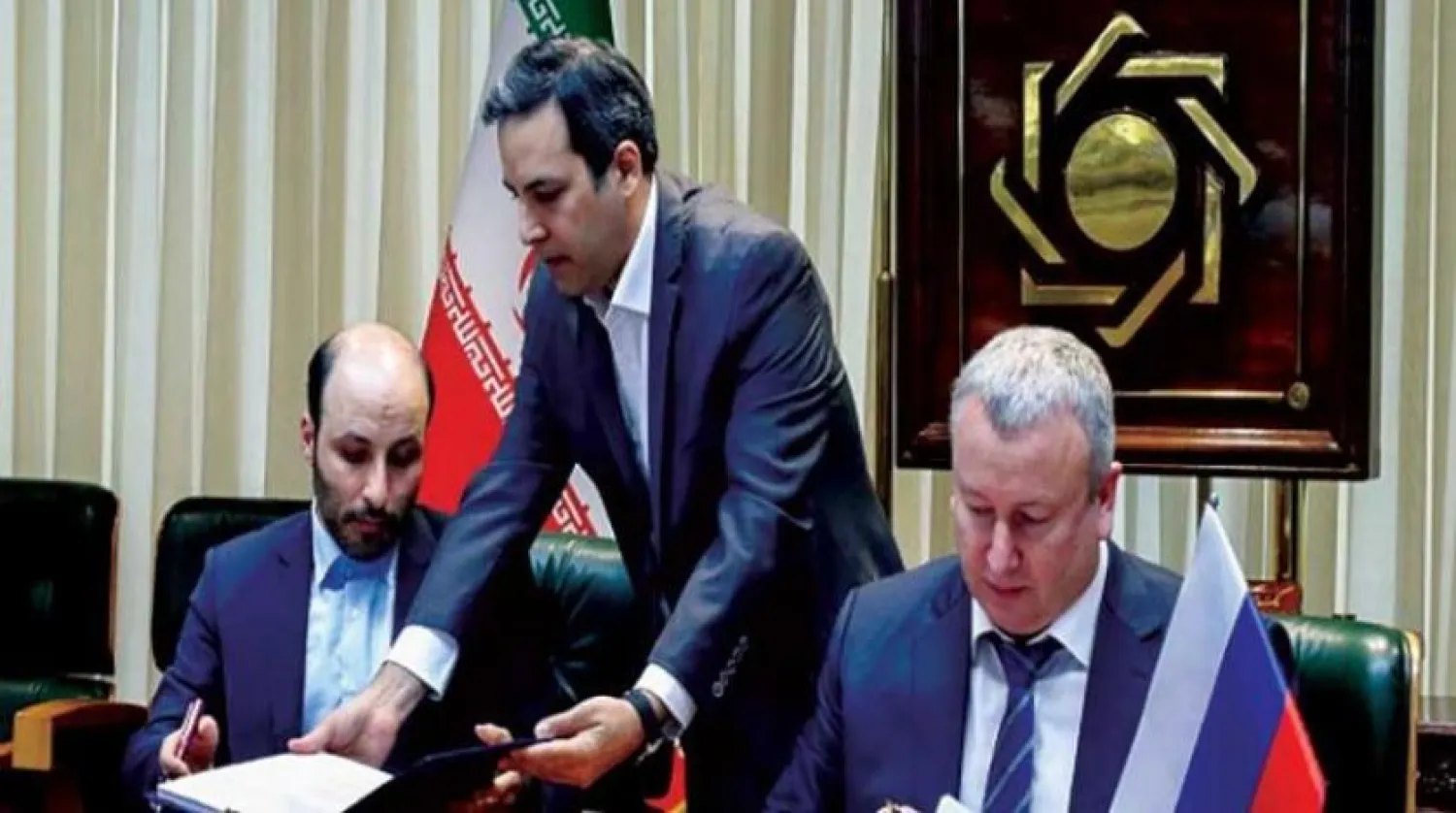 Russian and Iranian official sign the agreement in this photo released by Iran's Central Bank.