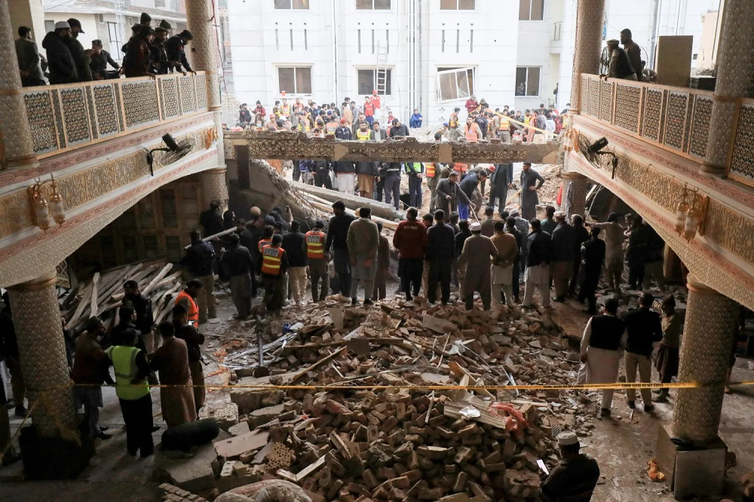 People and rescue workers gather to look for survivors under a collapsed roof, after a suicide blast in a mosque in Peshawar, Pakistan January 30, 2023. (Reuters)